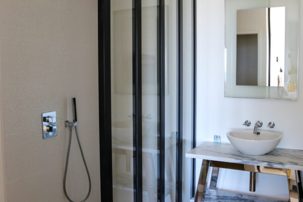 Salle de douche lumineuse avec vasque simple en marbre et toilettes