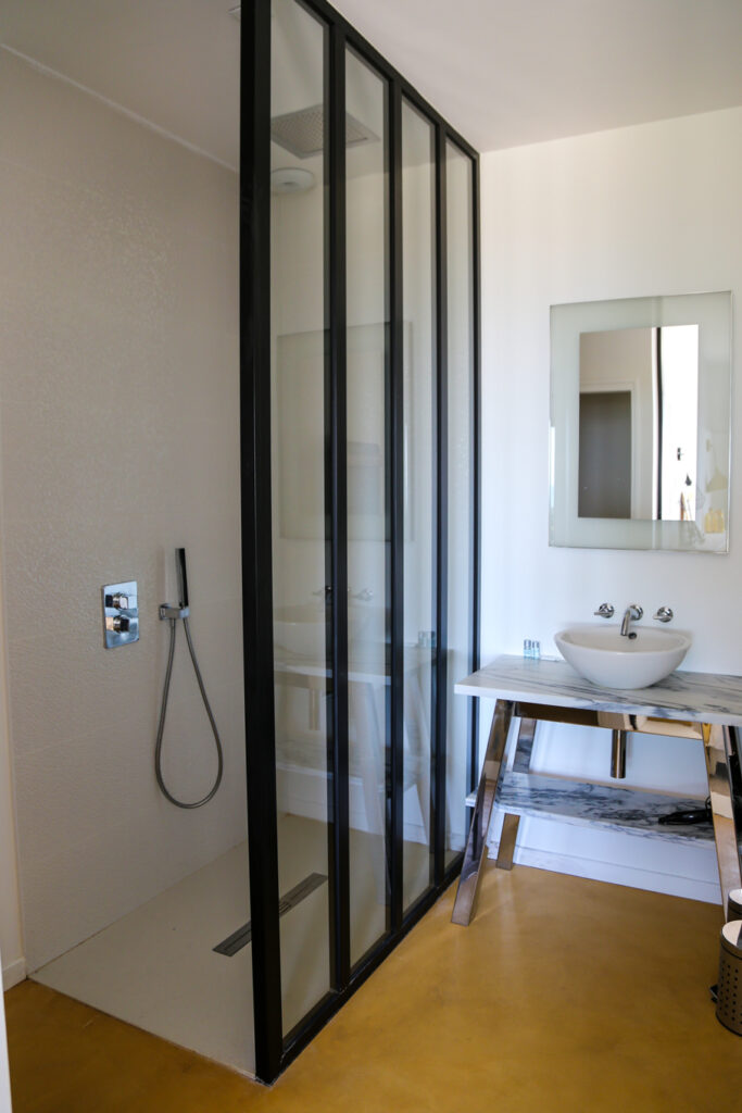 Salle de douche spacieuse et lumineuse avec ses toilettes individuelles et son lavabo en marbre