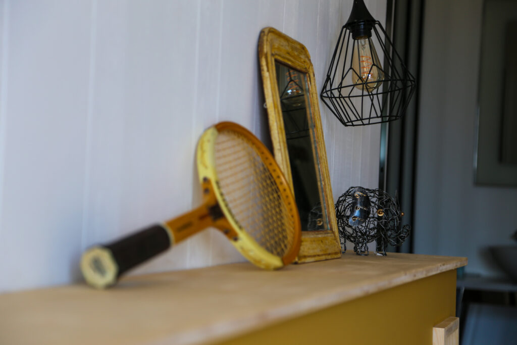 Ancienne raquette de tennis et miroir chinés pour décorer la tête de lit de la chambre Immortelle des dunes de la villa 180° mer