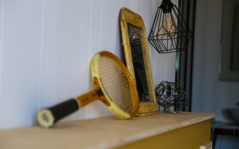 Ancienne raquette de tennis et miroir chinés pour décorer la tête de lit de la chambre Immortelle des dunes de la villa 180° mer