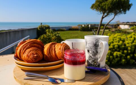 Plateau de petit déjeuner gourmand avec thé, croissants et confiture servie sur la terrasse vue mer